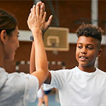 teacher and student high-fiving in gym class